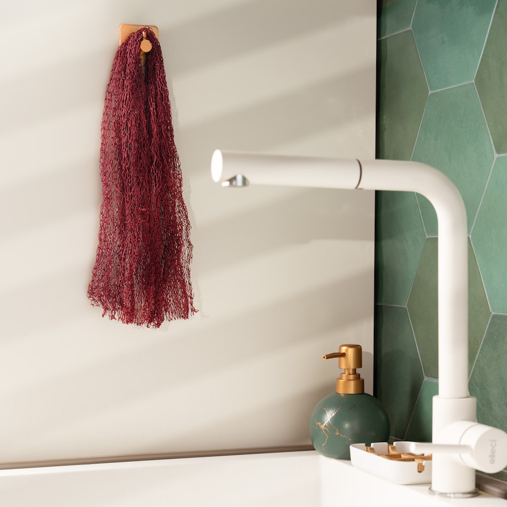 Ein Fischnetz Schwamm hängt ein einem Haken an der Wand neben der Küchenspüle.