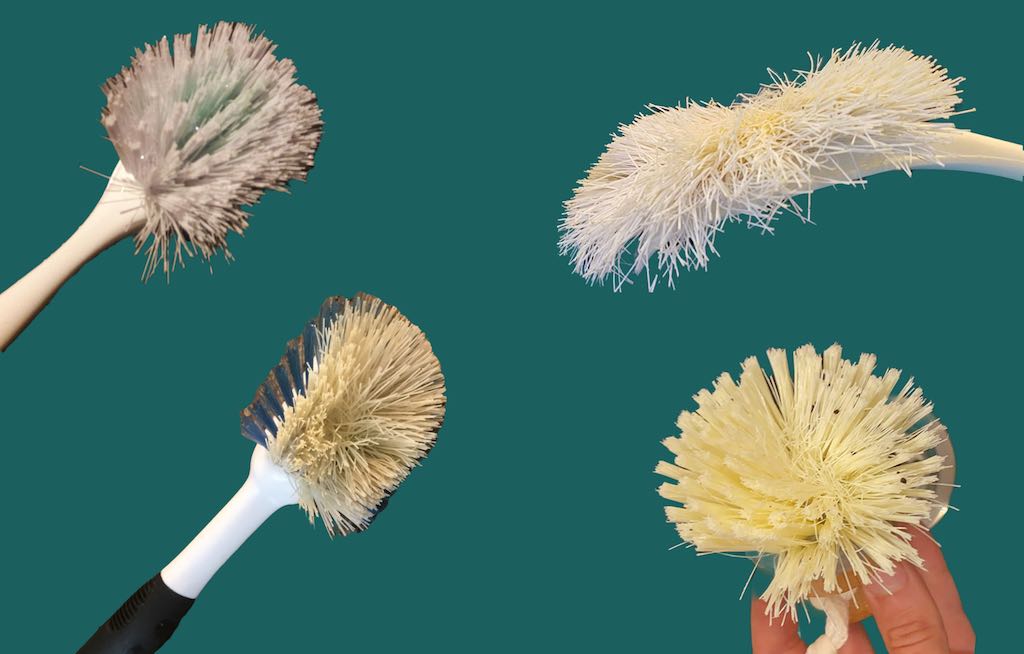 Vier gebrauchte Spülbürsten als Alternative zum stinkenden Küchenschwamm. Die vier Bürsten sind vor einen dunkelgrünen Hintergrund gezeigt.