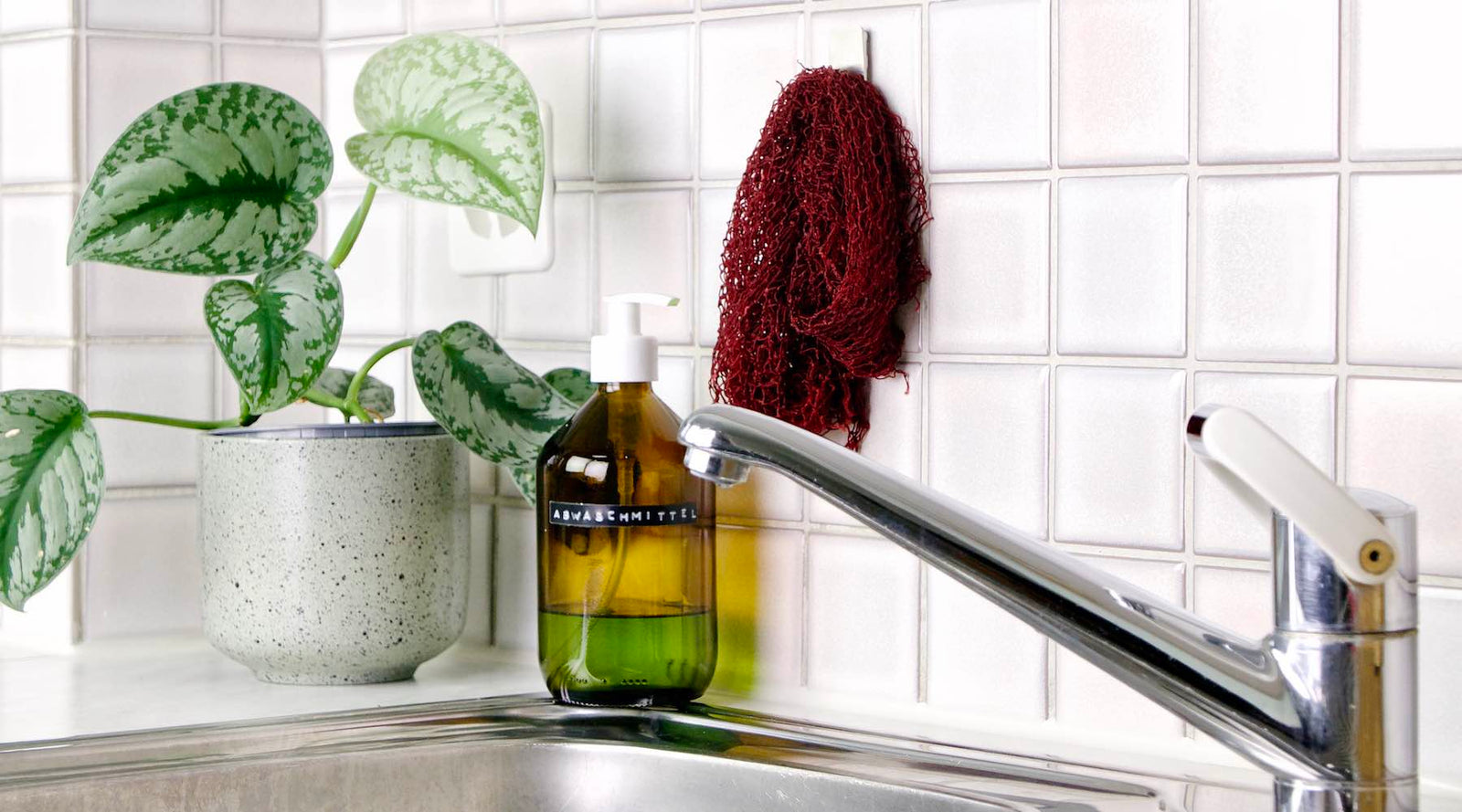 The Fischnetz dish sponge alternative is hanging on a kitchen wall over a kitchen sink.
