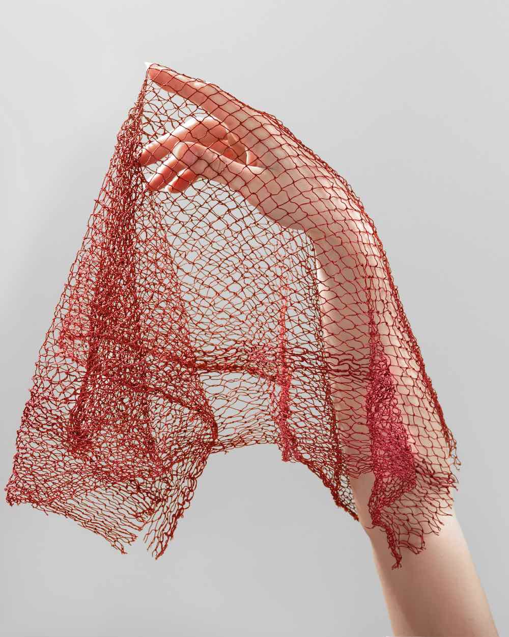 Ein rotes Fischnetz liegt künstlerisch über einem Arm.